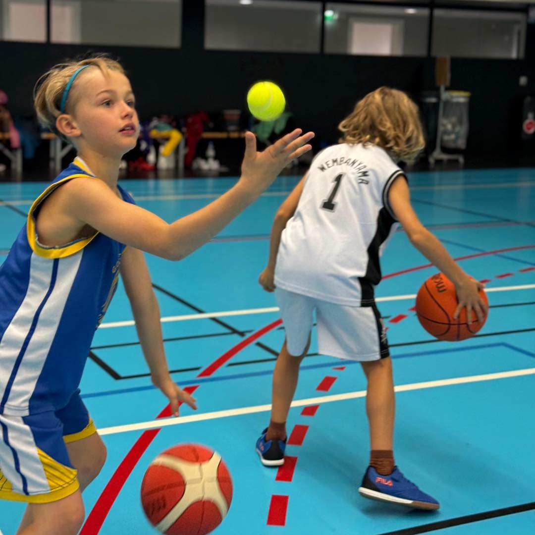 Deux jeunes réalisent un exercice avec ballon et balle de tennis.