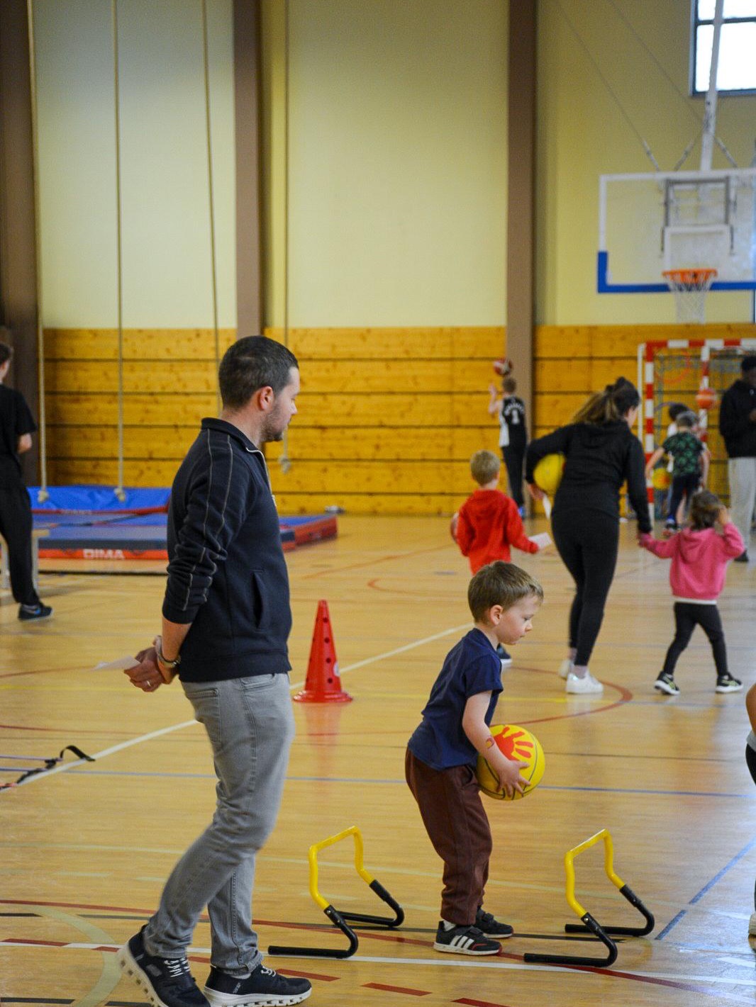 Un encadrant accompagne un atelier de motricité MiniBasket.