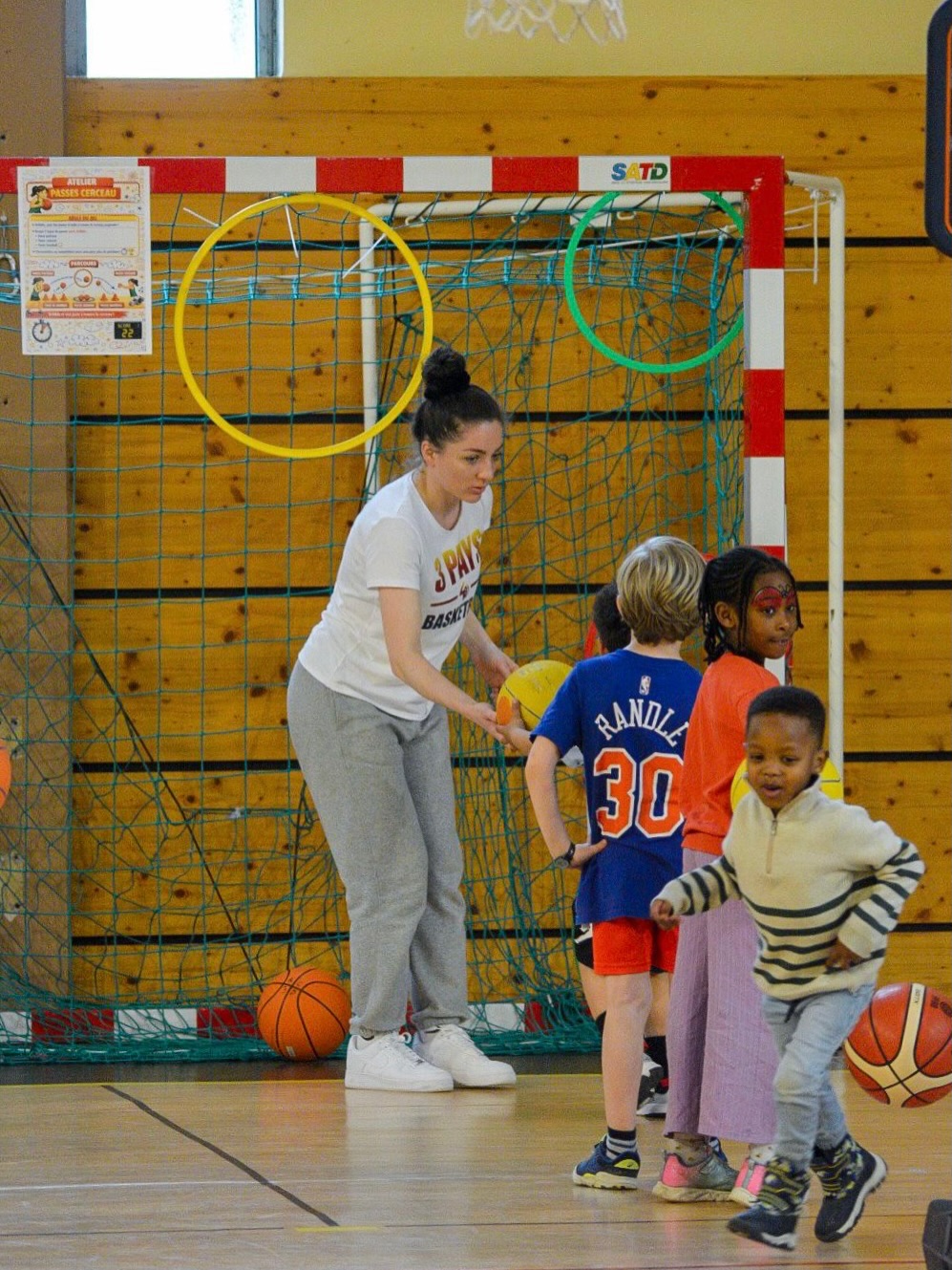 Une encadrante accompagne les enfants dans un atelier MiniBasket.