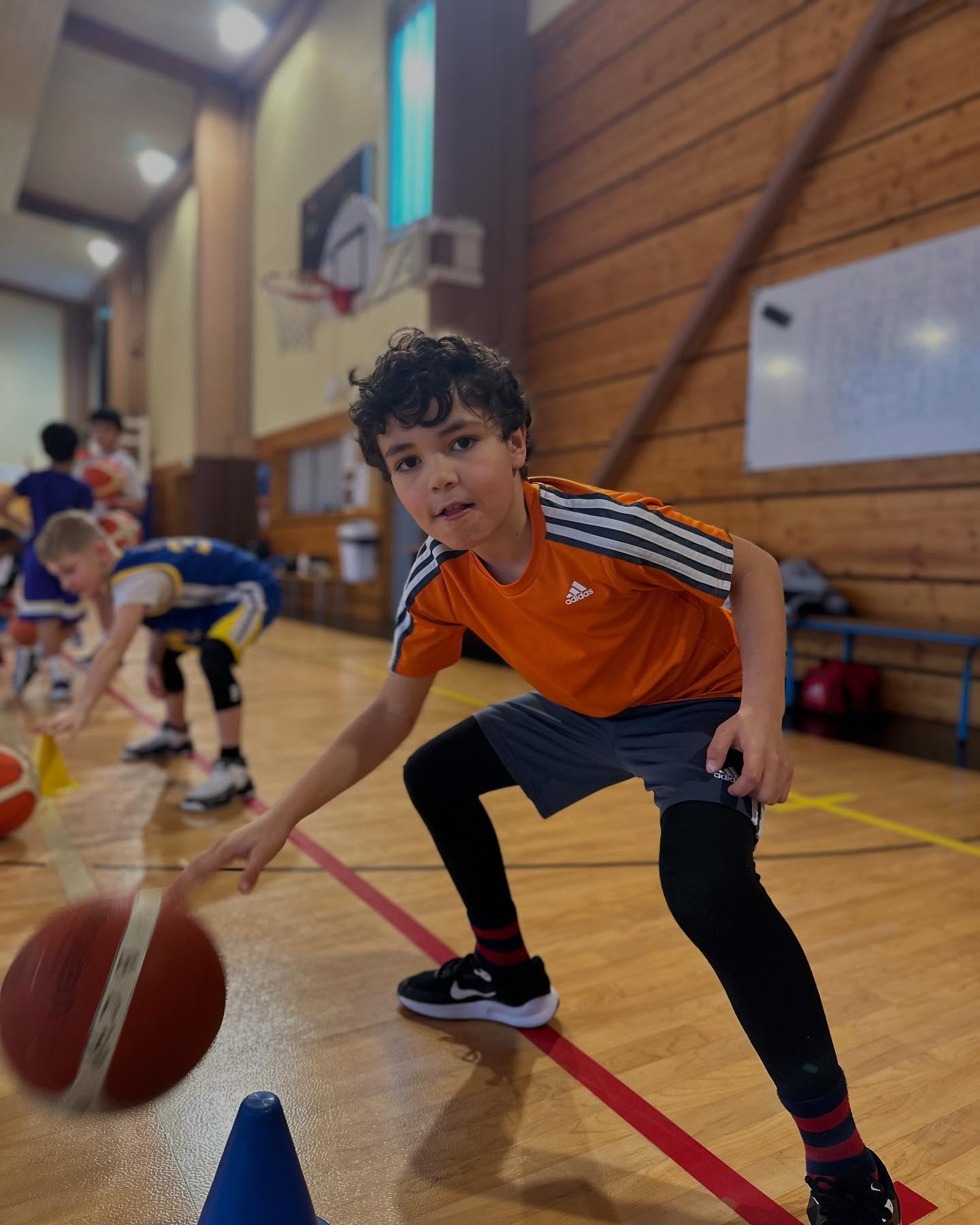 Jeune basketteur travaillant le dribble lors d’un atelier en salle.