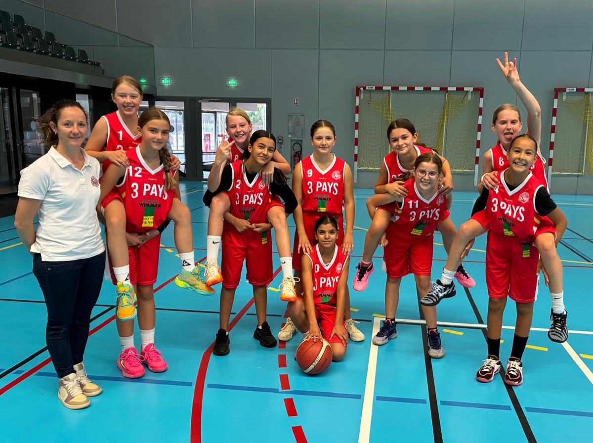 Jeunes en maillots rouges, réunis avec leur encadrement sur le terrain.