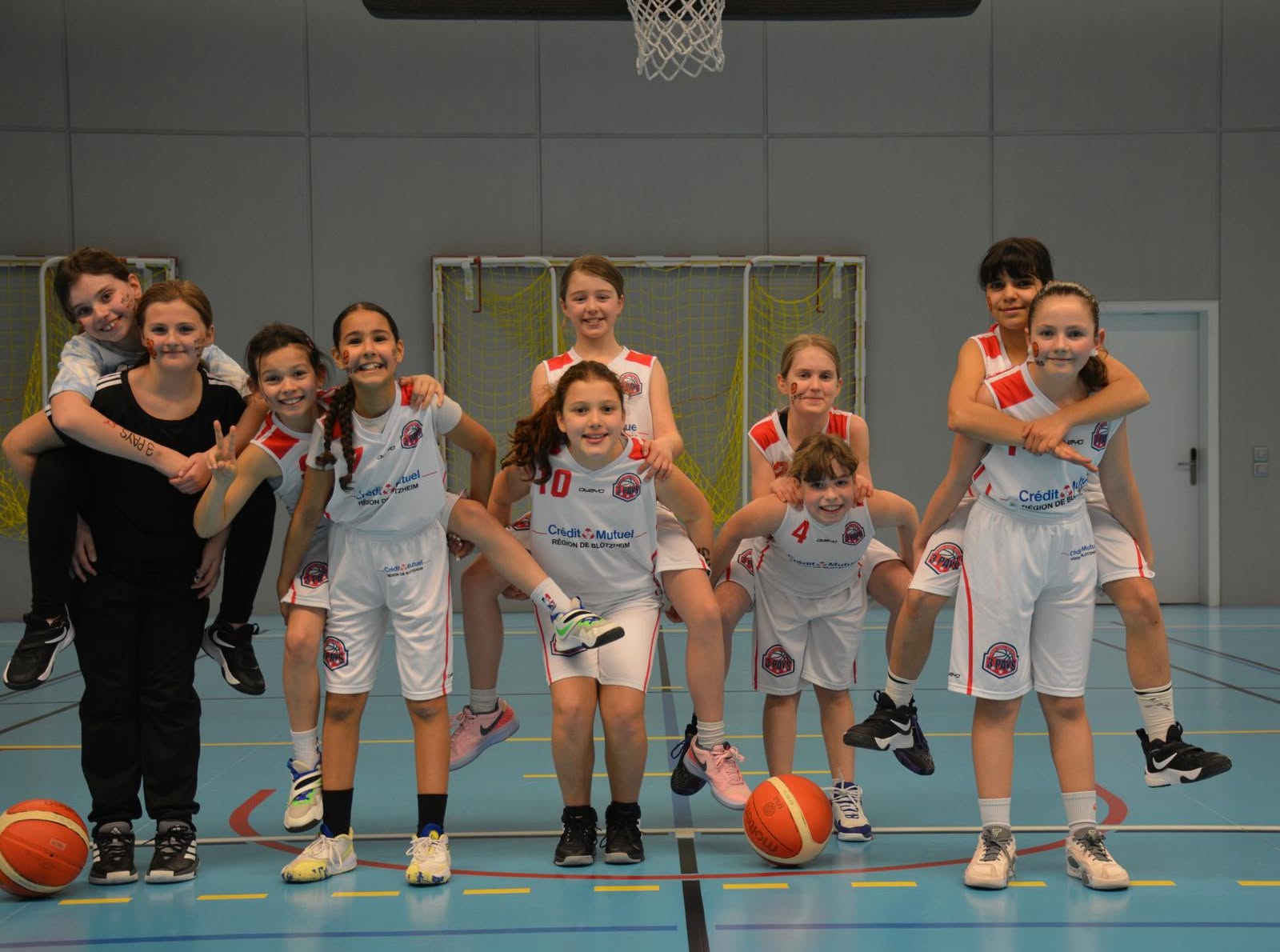 Jeunes basketteuses en tenue blanche et rouge, réunies sur le terrain.