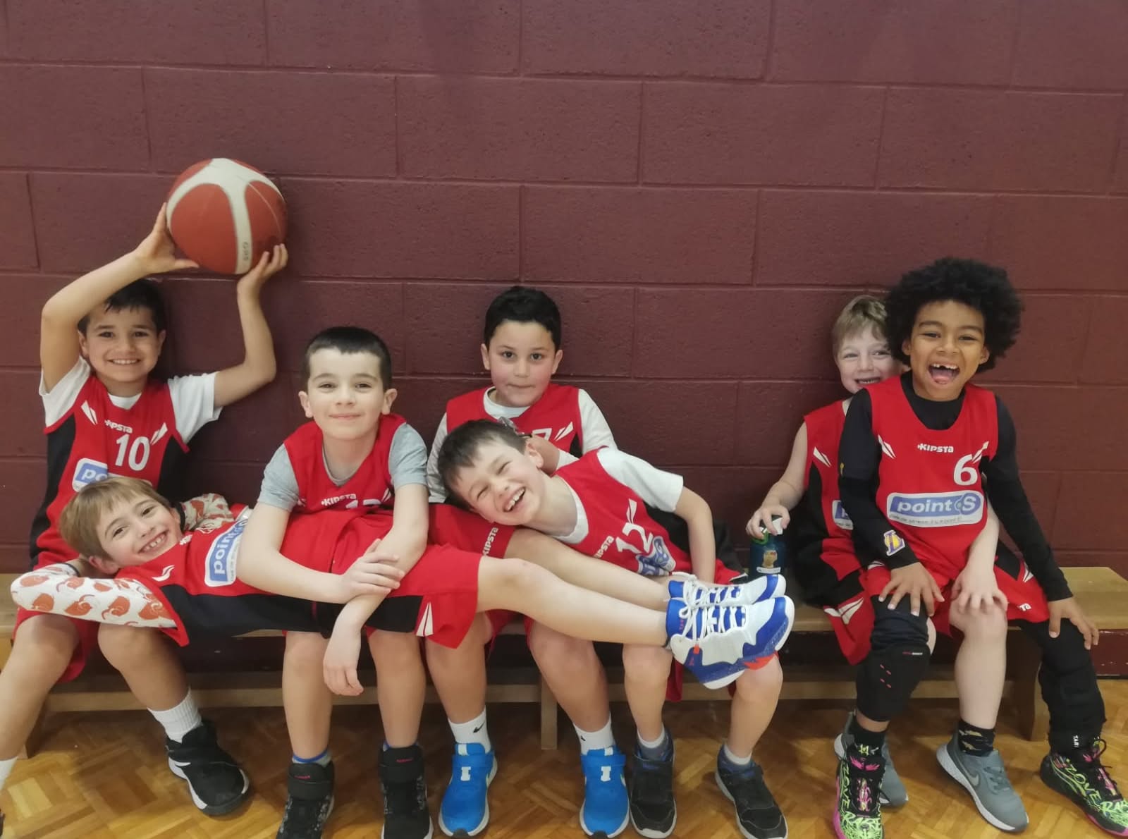 Jeunes basketteurs en tenue rouge, réunis près du terrain.